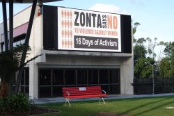 Red bench in front of the Zonta Says No billboard